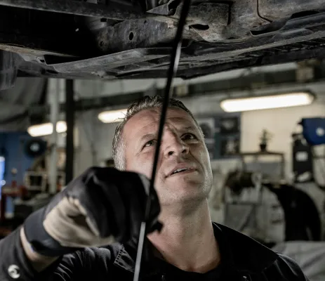 een automonteur controleert de onderkant van een auto